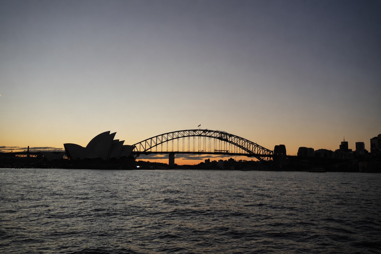 Sydney Opera House and Sydney Harbour Bridge silhouetted at sunset